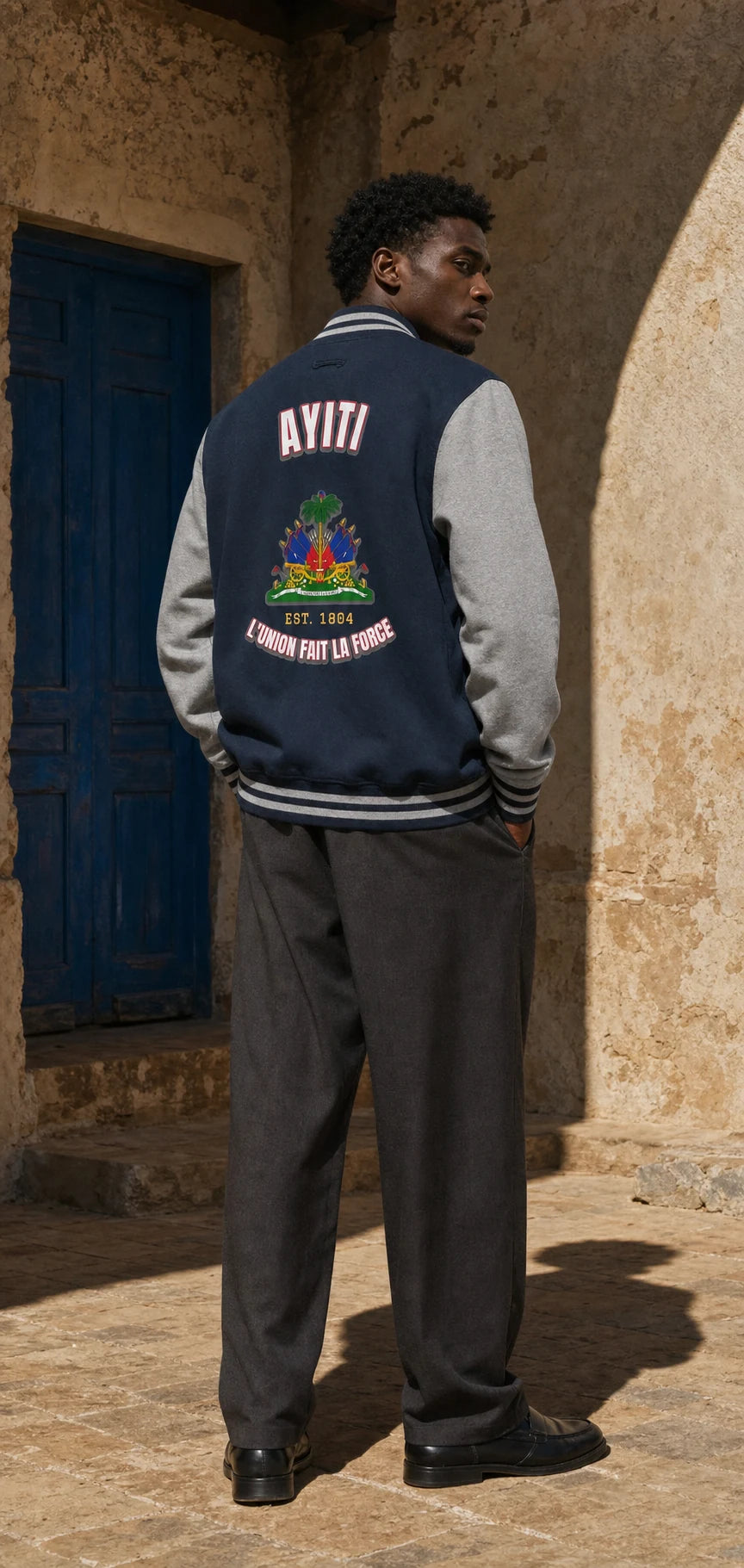 Model wearing the navy and grey L'Union AYITI varsity letterman in hard sunlight