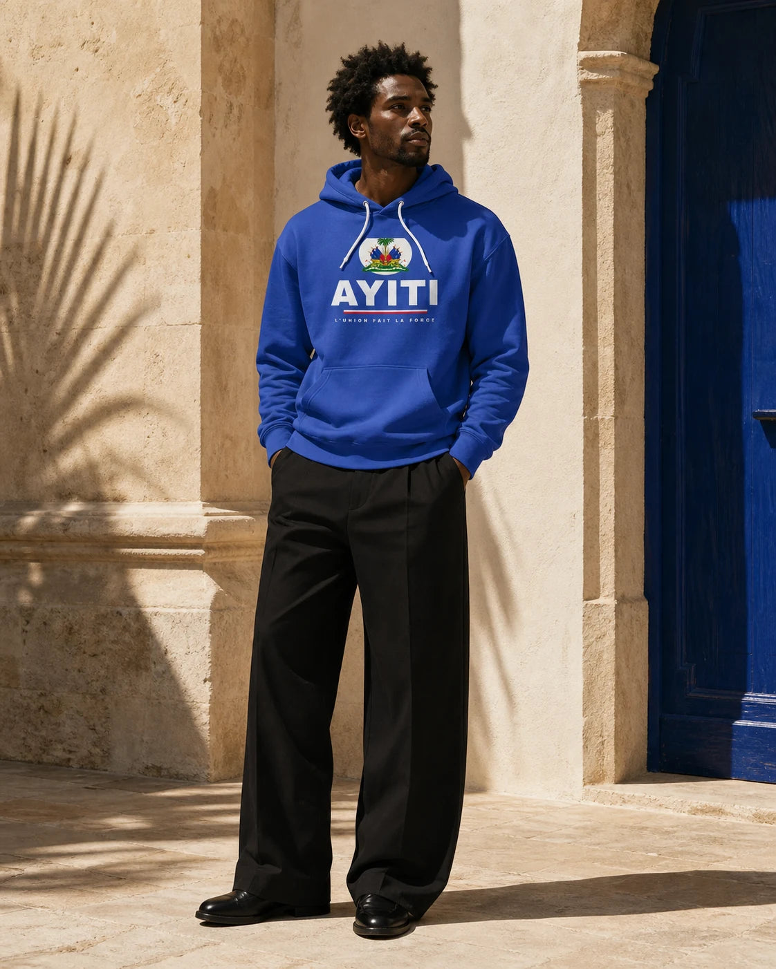 Model wearing the royal blue DRAPO AYITI color-block hoodie in Caribbean sunlight